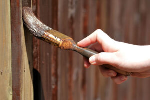 Zaun wird mit Holzlasur gestrichen