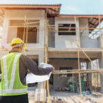 Arbeiter mit Plan vor Rohbau