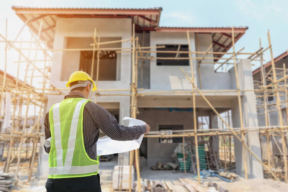 Arbeiter mit Plan vor Rohbau